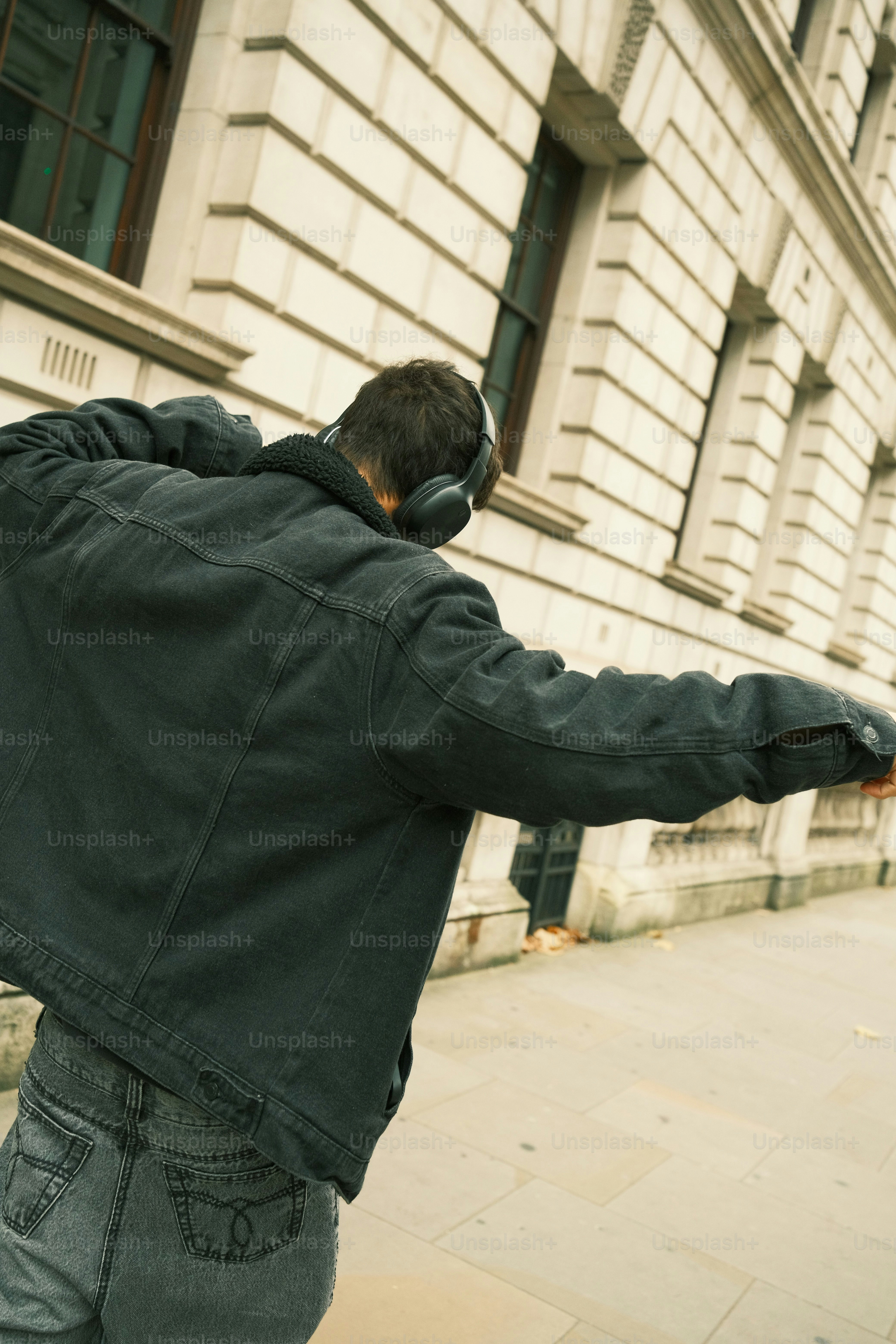 A man in a black jacket is skateboarding down the street